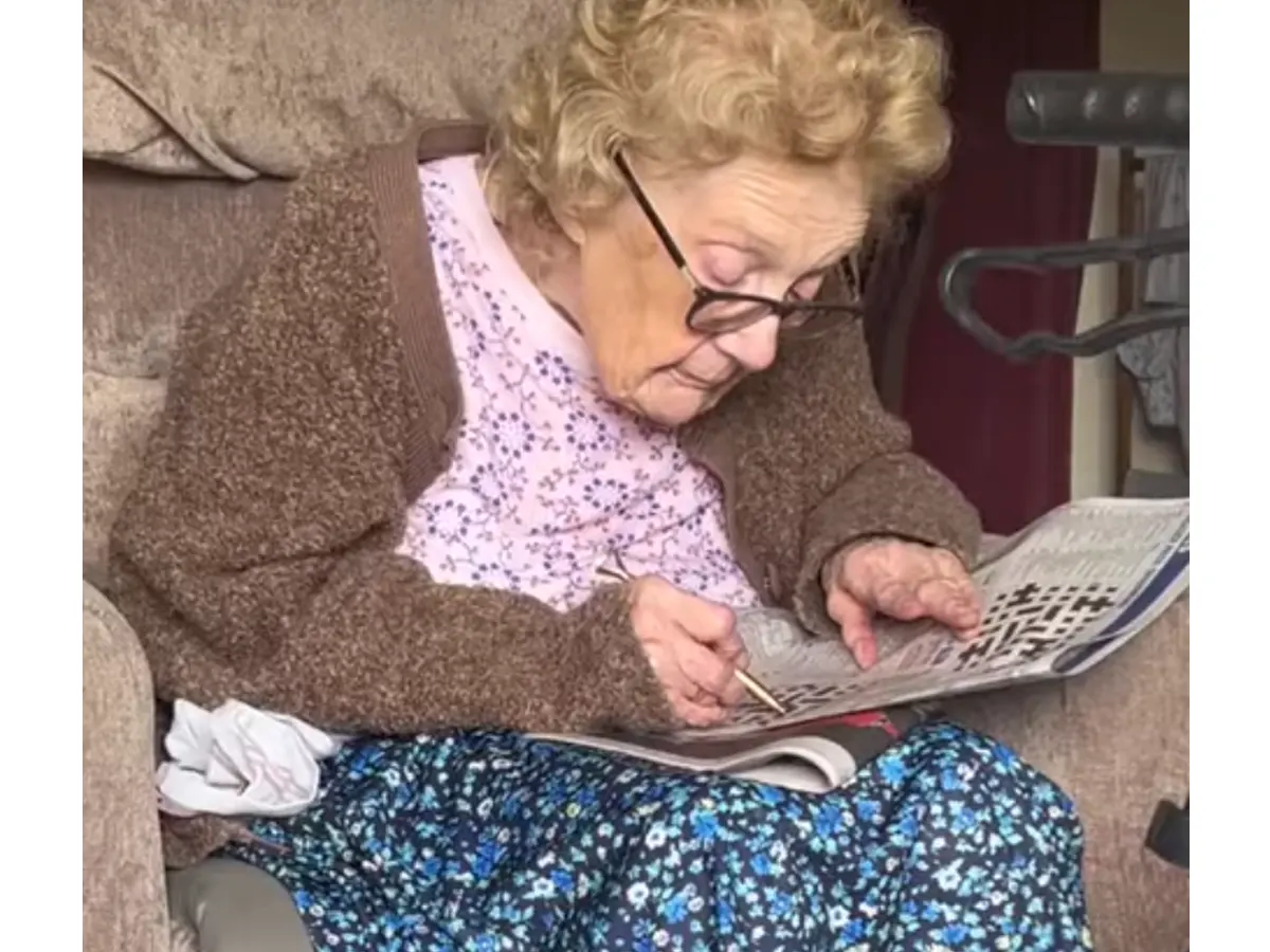Oude vrouw die kruiswoordpuzzel doet